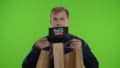 Surprised-man-showing-shopping-bags-and-Black-Friday-Deals-inscription-in-his-mouth.-Chroma-key
