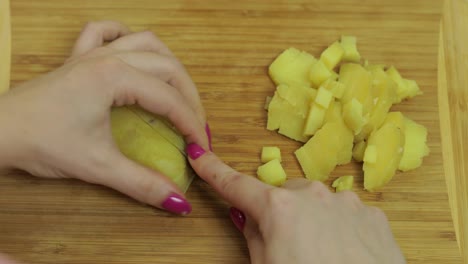 Female-housewife-hands-slicing-potatoes-into-pieces-in-the-kitchen