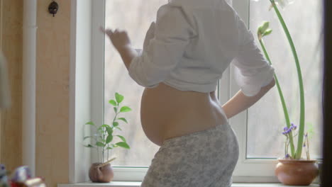 Happy-pregnant-woman-dancing-to-music-on-mobile