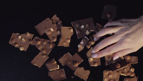 Woman-hand-takes-piece-of-chocolate-from-a-bunch-of-chocolate-pieces