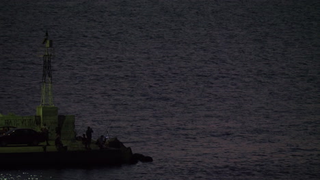 Men-fishing-from-the-quay-with-blinking-sea-light-Greece