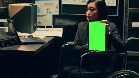 Detective-wheelchair-user-holds-greenscreen-layout-on-tablet
