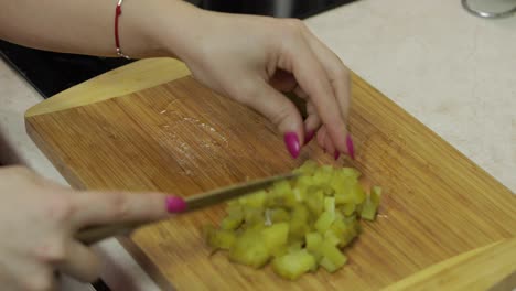 Female-housewife-hands-slicing-pickled-cucumber-into-pieces-in-the-kitchen