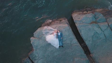 Wedding-newlyweds-couple-are-lying-on-a-mountainside-by-the-sea.-Aerial-shot