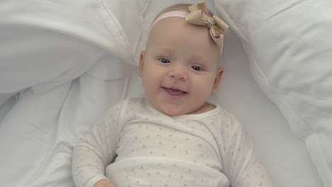 Smiling-blue-eyed-baby-girl-with-bow