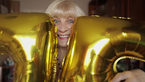 Cute-grandma-celebrates-her-birthday.-Holds-balloons-in-her-hands