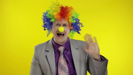 Clown-Geschäftsmann-Unternehmer-Chef-Mit-Perücke-Winkt-Mit-Den-Händen.-Gelber-Hintergrund
