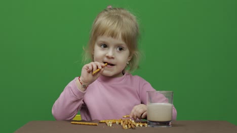 The-child-eats-cookies.-A-little-girl-is-eating-cookies-sitting-on-the-table.