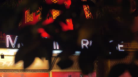 Moulin-Rouge-view-through-tree-leaves-at-night-Paris