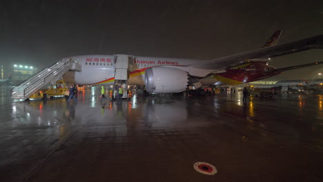 Pasajeros-Que-Desembarcan-Del-Avión-De-Hainan-Airlines-Por-Las-Escaleras-De-Aire-Durante-La-Noche