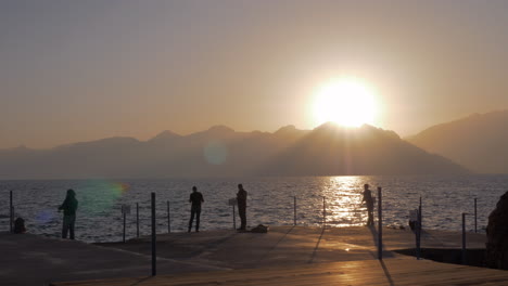 Männer-Angeln-Auf-Dem-Pier-Bei-Sonnenuntergang