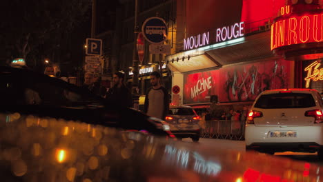 People-and-cars-in-night-street-with-famous-Moulin-Rouge-Paris