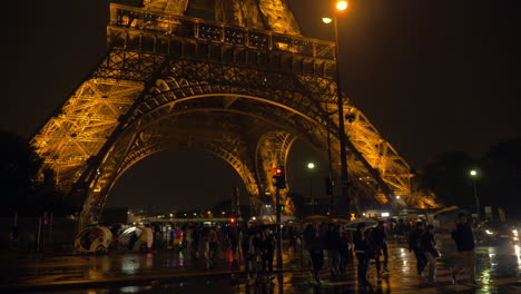 People-crossing-the-road-near-Eiffel-Tower-at-rainy-night-in-Paris
