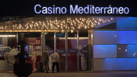 Zwei-Männer-Betreten-Nachts-Das-Casino-Mediterraneo