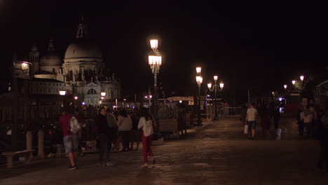 Street-view-people-and-Cathedral-of-Santa-Maria-della-Salute-in-night-Venice