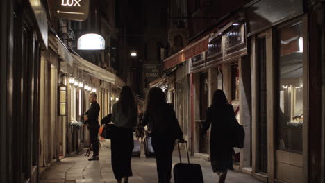 Vista-Nocturna-De-Una-Calle-Estrecha-De-La-Ciudad-Con-Gente-Caminando-Italia