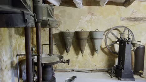 Tools-of-an-old-workshop-in-France-for-pressing-olives-for-vinegar-and-oil-or-pressing-for-wine-with-old-wooden-funnels-in-a-small-room