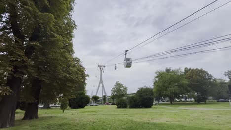 Cable-car-station-with-gray-pillars-and-small-gondolas-over-a-meadow-with-trees-in-Cologne-Germany