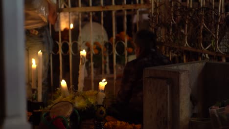 An-elderly-man-sitting-next-to-candles-on-the-graveyard-in-Mexico,-celebrating-day-of-the-dead