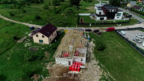 Drone-shot-circling-a-unfinished-house-roof-construction-area,-in-a-neighborhood