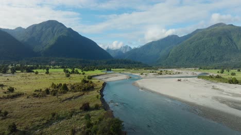 Aerial-drone-flight-over-remote-wilderness-of-Southern-Alps-mountainous-landscape-with-braided-river-on-the-wild-and-rugged-West-Coast-of-South-Island,-New-Zealand-Aotearoa