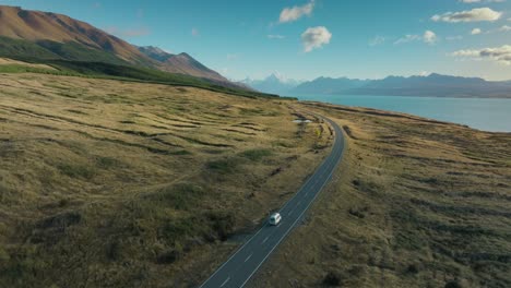 Aerial-view-of-white-campervan-traveling-along-remote-scenic-road-with-a-view-of-Aoraki-Mount-Cook-in-South-Island-of-New-Zealand-Aotearoa