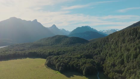 Reverse-aerial-drone-view-of-tree-covered-landscape-of-rugged,-wild-and-remote-Southern-Alps-mountain-ranges-in-Glenorchy,-New-Zealand-Aotearoa