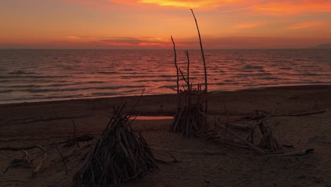 Sandy-beach-during-sunset-with-driftwood-tipis