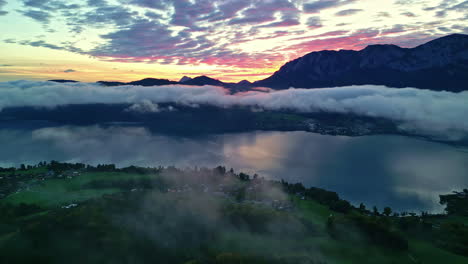 Sunrise-over-the-misty-Attersee-Lake-in-Austria-with-a-village-on-the-shore---aerial-push-in