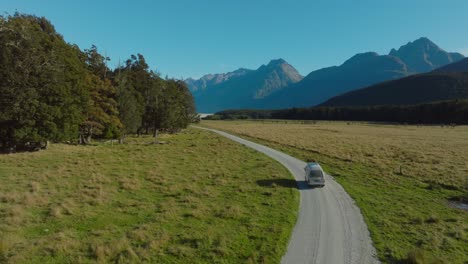 Aerial-flight-following-a-tourist-campervan-on-remote-rural-road-in-Southern-Alps-mountainous-landscape-of-Glenorchy,-South-Island-in-New-Zealand-Aotearoa