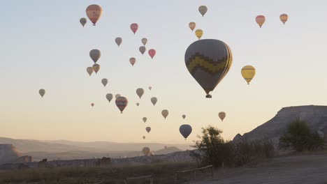Hot-air-balloons-float-across-golden-hour-sunrise-sky-pan-shot