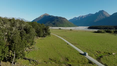Aerial-view-of-tourist-campervan-traveling-on-remote-road-through-landscape-of-Dart-Valley-in-remote-Glenorchy,-location-for-Isengard-from-Lord-of-the-Rings,-South-Island-of-New-Zealand-Aotearoa
