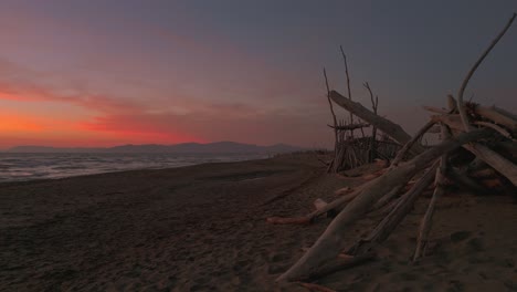 Holztipis-An-Einem-Sandstrand-Bei-Sonnenuntergang
