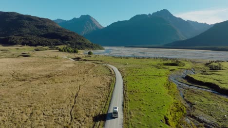 Scenic-aerial-view-of-campervan-traveling-through-green-plateau-of-rugged-mountainous-landscape-exploring-Isengard-location-from-Lord-of-the-Rings-in-Glenorchy,-South-Island-of-New-Zealand-Aotearoa