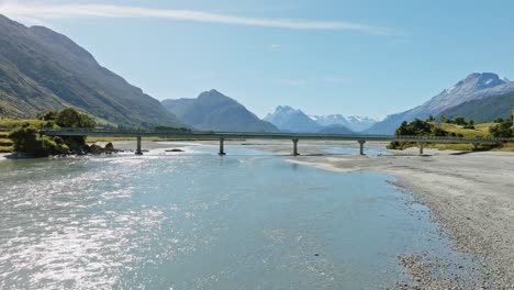 Fast-aerial-flight-over-scenic,-shallow-and-winding-Dart-River-Te-Awa-Whakatipu-braided-river-system-with-the-rugged-Southern-Alps-mountains-in-Glenorchy,-South-Island-of-New-Zealand-Aotearoa