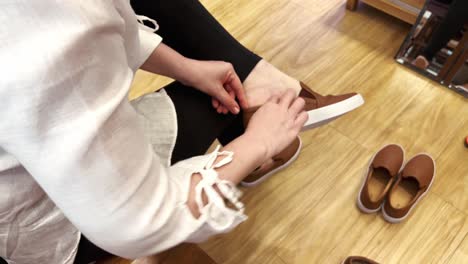 Woman-sitting-and-trying-on-shoes-in-a-fashion-store