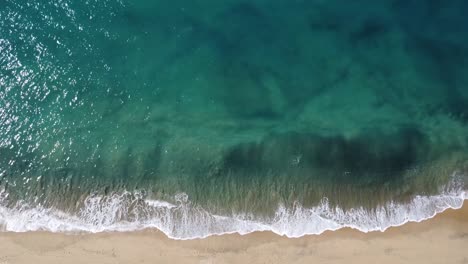 Aerial-overhead-view-of-waves-reaching-a-sandy-beach