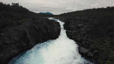 Luftklarer-Blauer-Wasserfallfluss-Hlauptungufoss-Island,-Der-über-Schäumende-Wellen-Fliegt