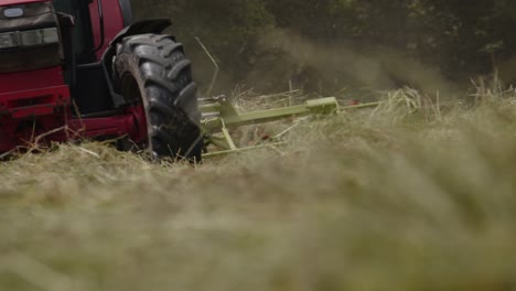 Low-POV-handheld-shot-of-tractor-mowing-grass