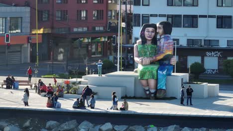 Familien-Und-Menschen-Gehen-Spazieren,-Machen-Fotos-Und-Genießen-Den-Sonnigen-Tag-Rund-Um-Die-Skulptur-„sentados-Frente-Al-Mar“-In-Puerto-Montt,-Chile