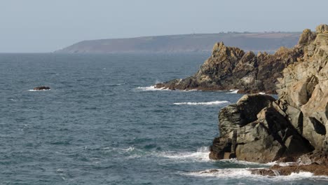 extra-wide-shot-waves-crashing-over-rocks-at-Piskies-Cove-by-HMS-Warspite-monument