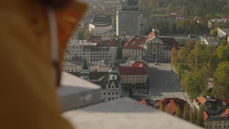 Selektiver-Fokus-Auf-Den-Kongressplatz-Von-Der-Burg-Von-Ljubljana-Aus,-Während-Ein-Nicht-Erkennbarer-Tourist-Das-Panorama-Beobachtet