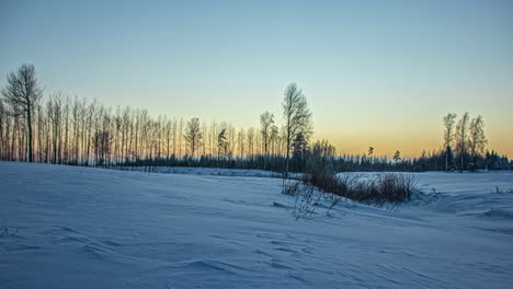 Zeitrafferaufnahme-Des-Goldenen-Sonnenuntergangs-Am-Farbenprächtigen-Himmel-über-Schneebedeckten-Landwirtschaftlichen-Feldern-Entlang-Der-Ländlichen-Landschaft-Am-Abend