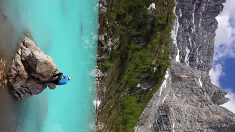 Man-climbing-rocky-mound-in-blue-glacial-waters-of-Lake-Sorapis