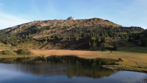 Panoramic-view-of-a-hill-captured-from-a-lake-with-grassy-landscape-and-few-trees