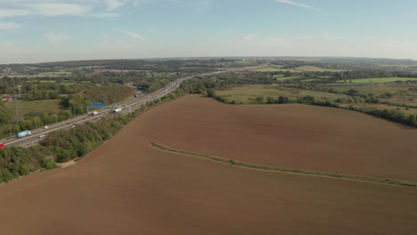 Aerial-shot-over-farm-land-towards-M25-motorway