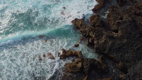Scenic-aerial-video-of-calm-and-gentle-turquoise-waves-hitting-coastal-volcanic-rock---Gran-Canaria,-Spain