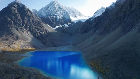 A-bright-blue-glacier-lake-Bleisvatnet-in-a-mountainous-Lynge-Alpen-valley-with-snowy-peaks