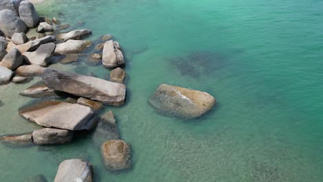 Flying-over-calm-waters-with-big-rocks-on-the-left-side-of-the-frame