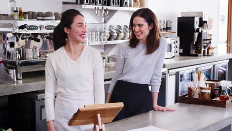 Two-female-business-owners-behind-the-counter-at-their-cafe